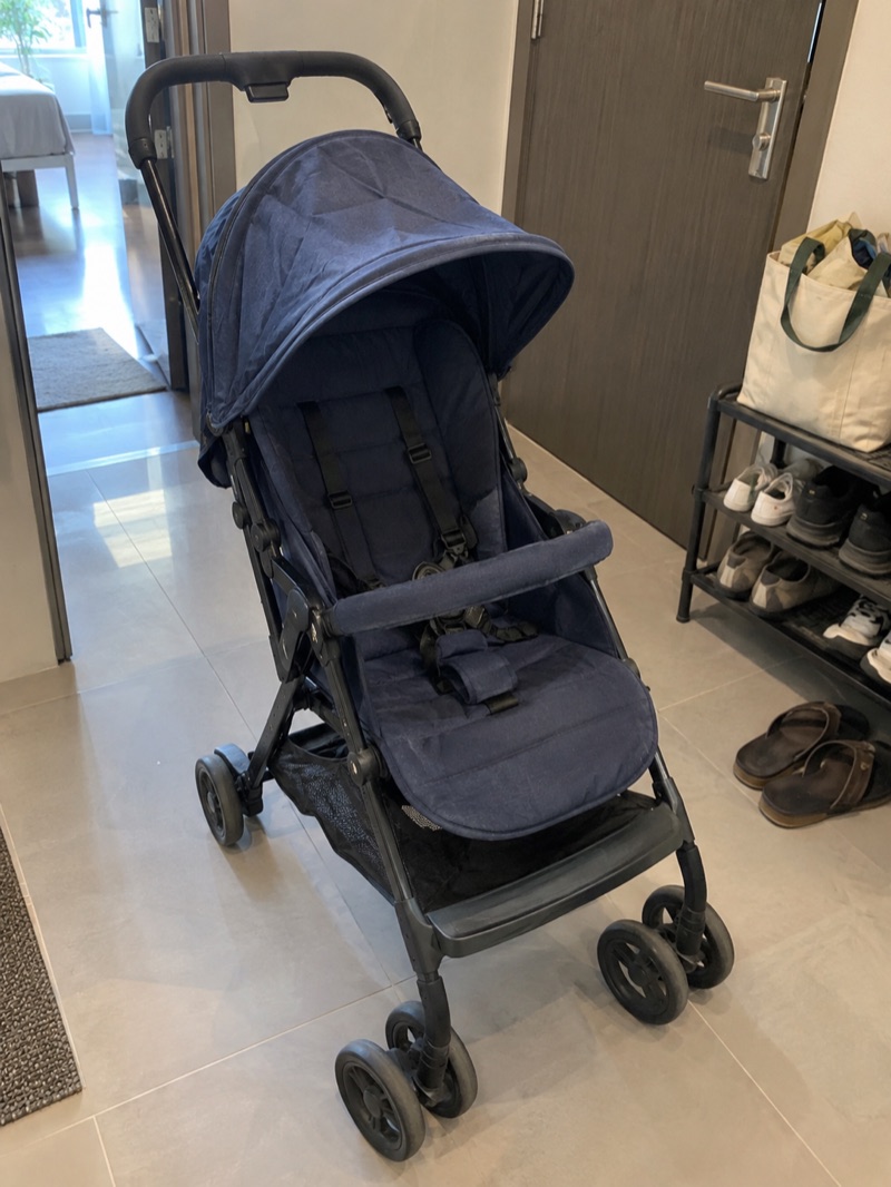 Illustrative phone snapshot of a secondhand navy stroller at home