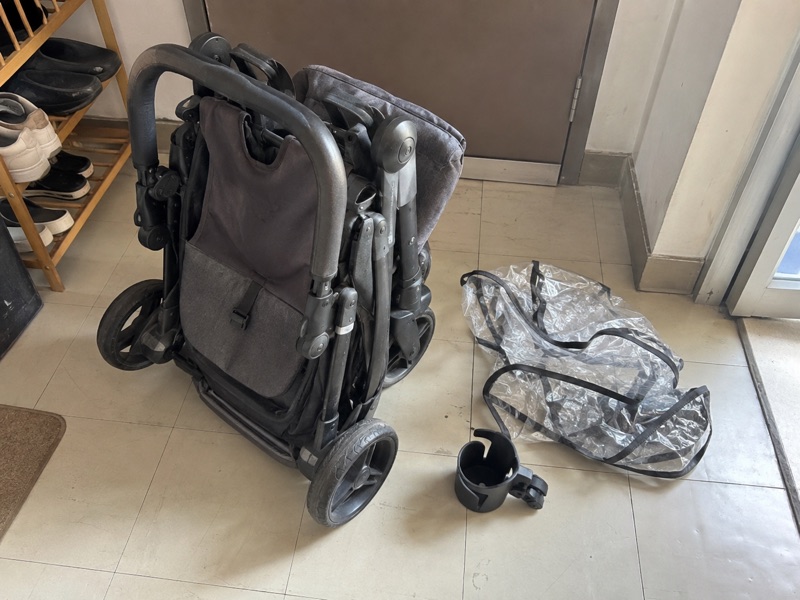 Illustrative phone snapshot of a folded used stroller and accessories ready for handover