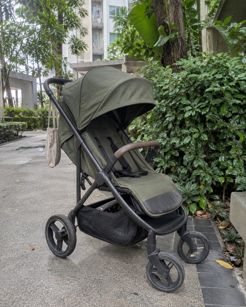 Illustrative phone snapshot of a used olive stroller in a condo garden