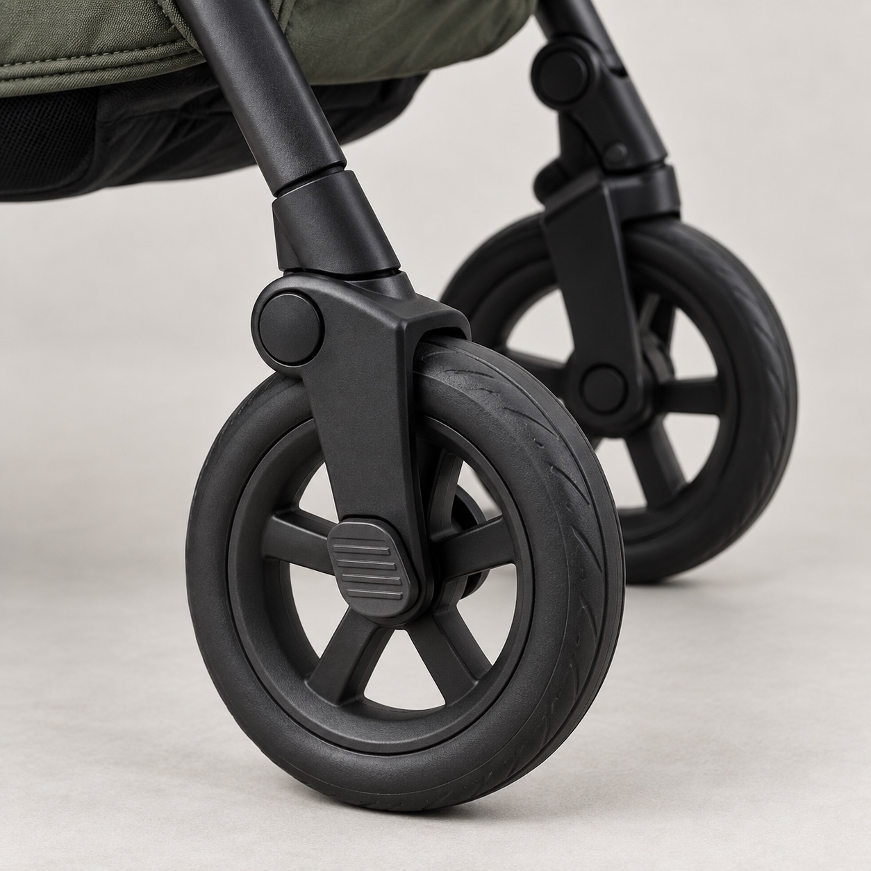 Close-up of two black stroller wheels, forks and brake pedal