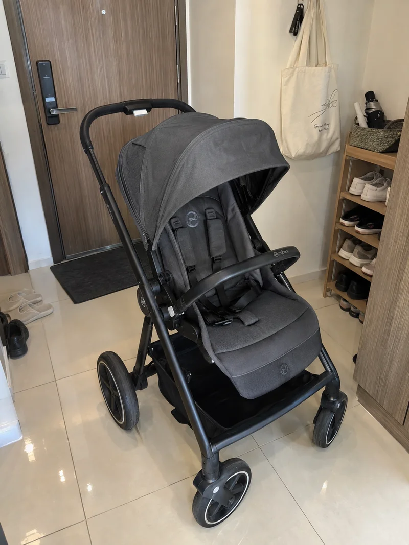 Generated phone-style illustration of a grey CYBEX stroller beside a condo shoe rack